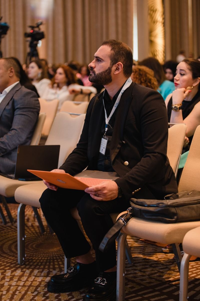 Focused man in suit attends conference, engaging in session.